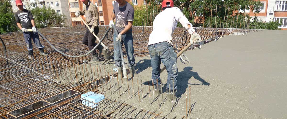 рабочие на стройке заливают бетонную стяжку